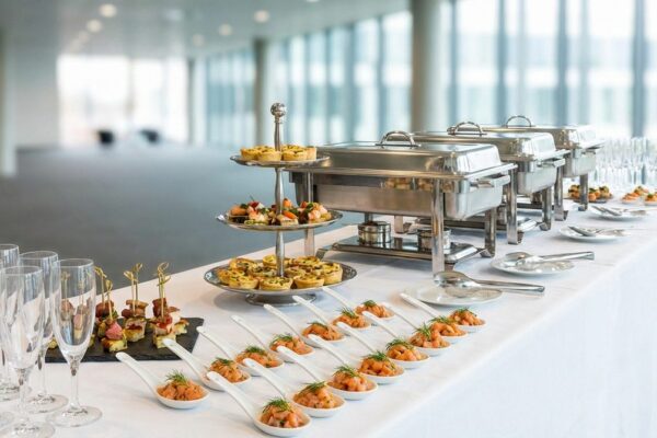 Catering-Buffet mit Fingerfood auf Etageren, Lachs-Häppchen auf Löffeln und Chafing Dishes